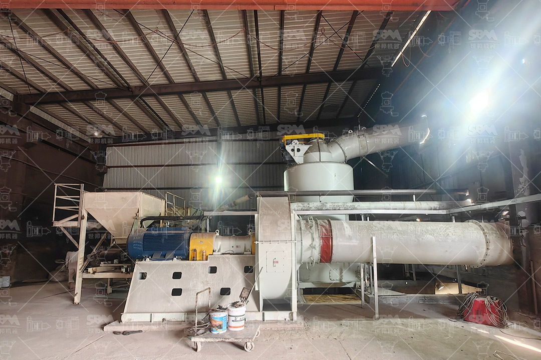 A large pile of white mud, a chalky by-product from a paper mill, awaiting processing.