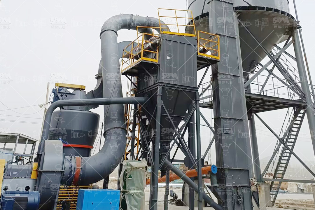 A large industrial pile of raw asphalt coke material at a processing facility.